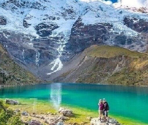 Two people standing on a rock near the water.