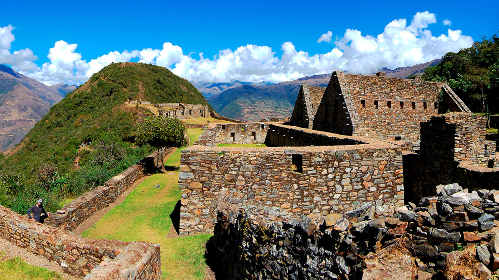 A stone wall and some buildings on top of a hill.