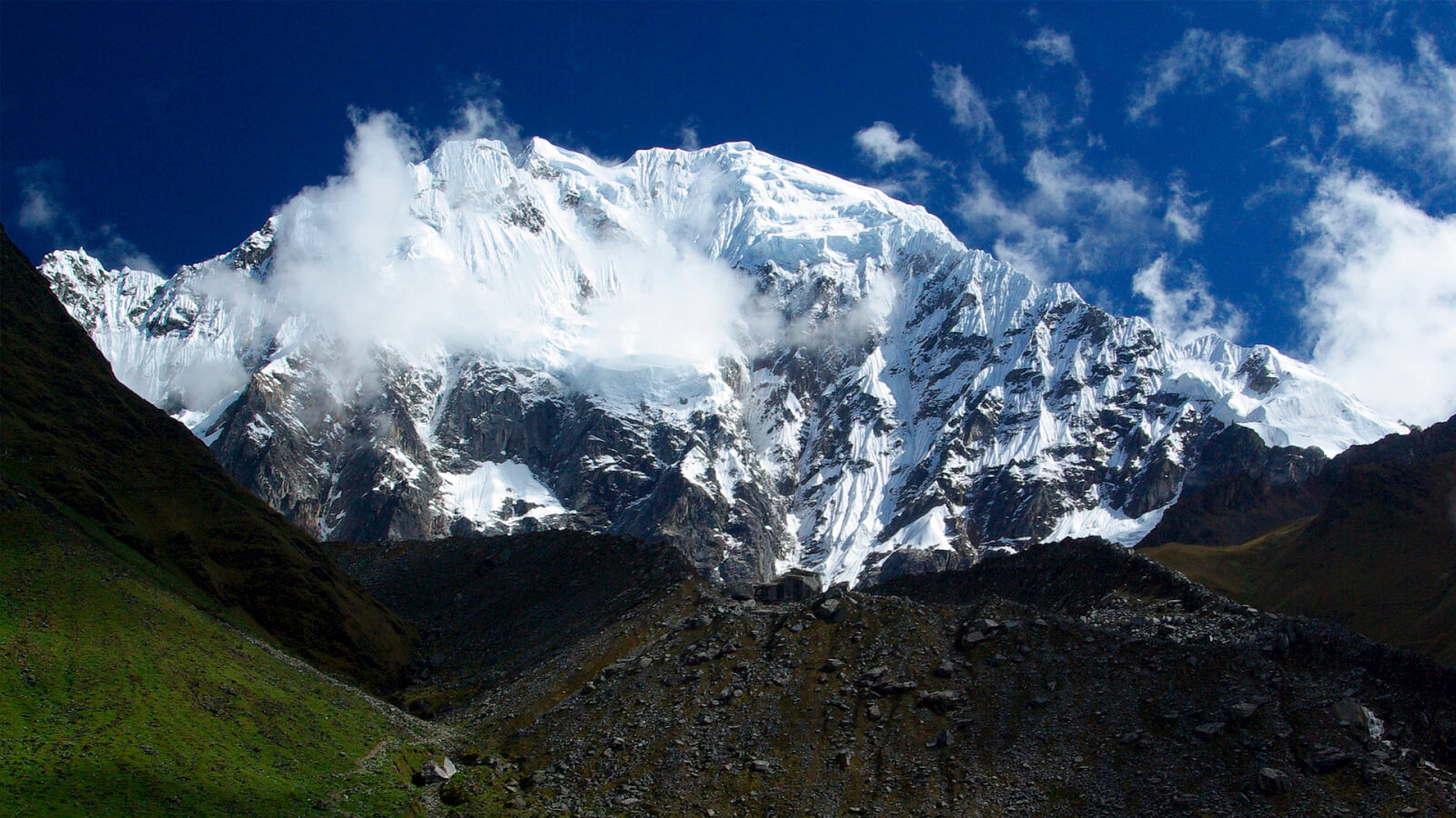 A mountain with snow on it and clouds in the sky.