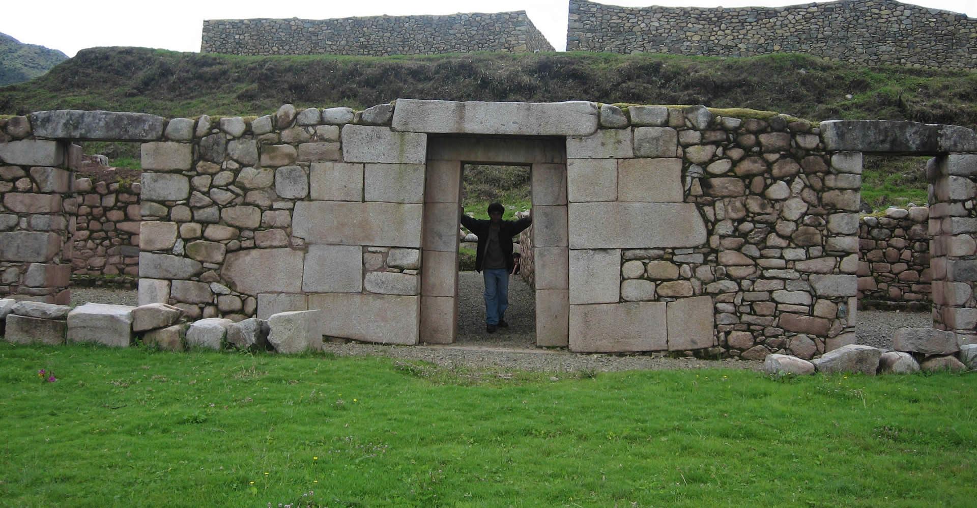 A man standing in front of an entrance to a stone building.