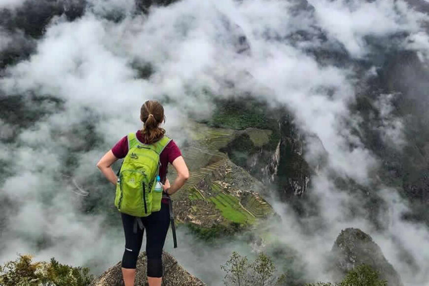 Woman hiker overlooking Machu Picchu in clouds.