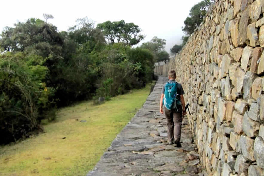 Hiker walking along ancient stone wall.