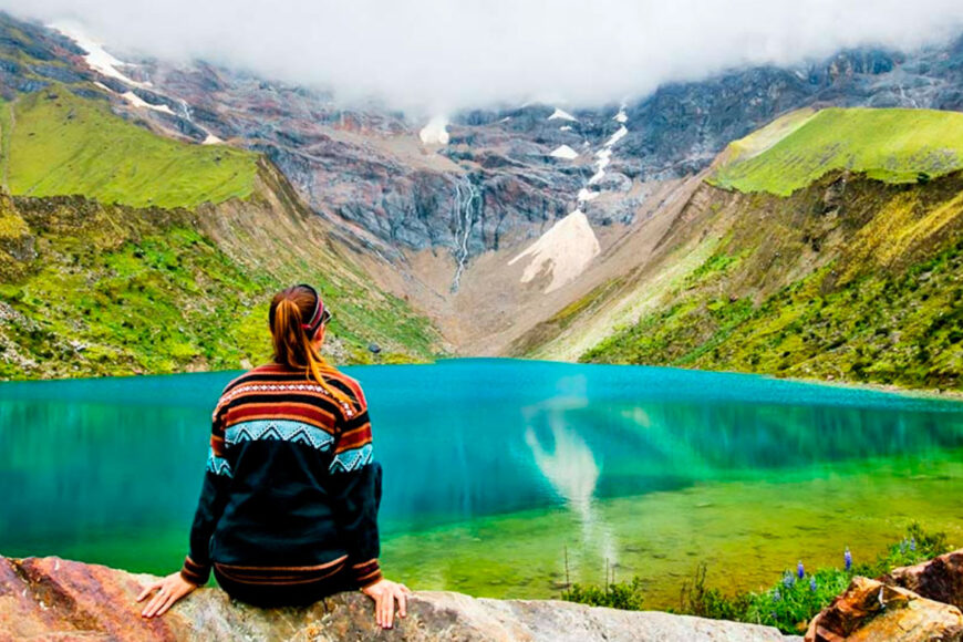 Woman admiring turquoise mountain lake.