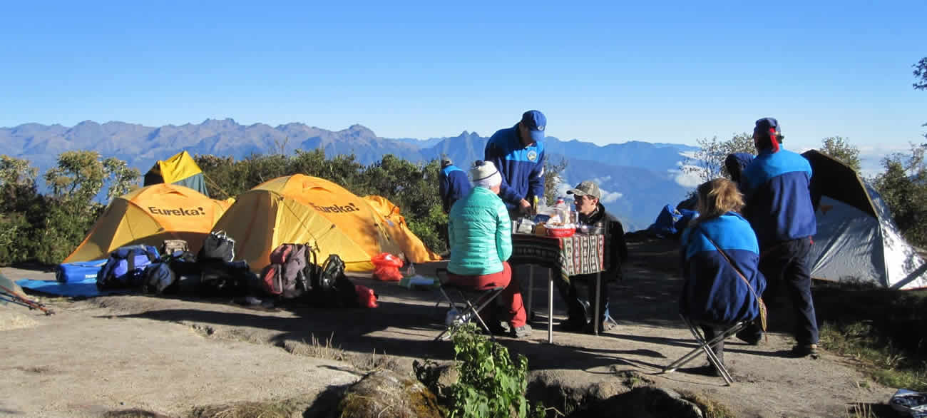 Hikers enjoying a meal with mountain views.
